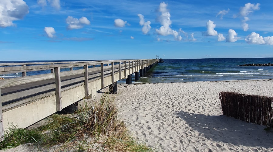Paar entspannt im Bett und isst Erdbeeren unter einem Wandbild mit Fischerboot